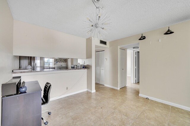 unfurnished office featuring a chandelier, a textured ceiling, and light tile patterned floors