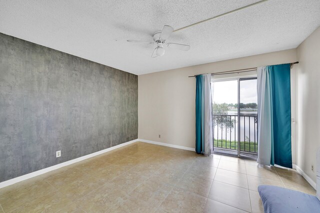 empty room with a water view, ceiling fan, and a textured ceiling