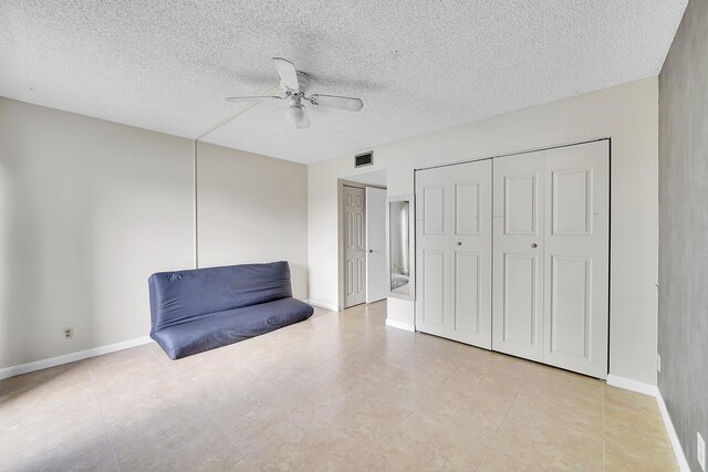 unfurnished bedroom with ceiling fan and a textured ceiling