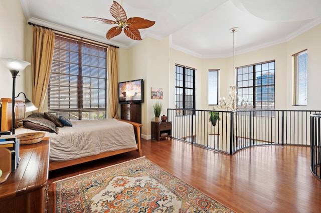 bedroom featuring hardwood / wood-style floors, ceiling fan with notable chandelier, crown molding, and multiple windows