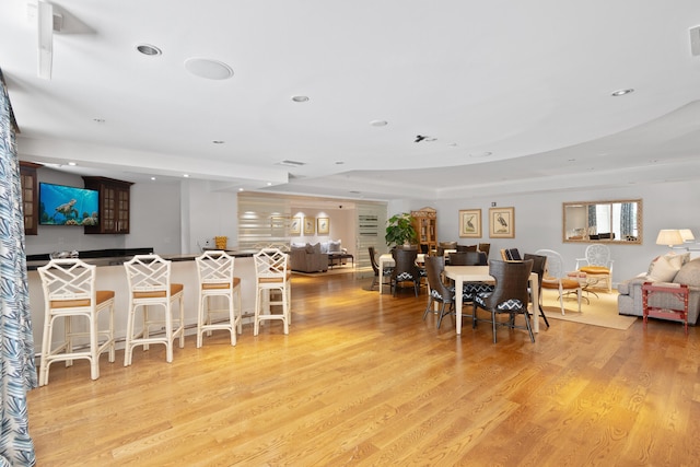 dining space featuring light hardwood / wood-style floors and a raised ceiling