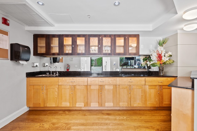 bar featuring sink, dark stone counters, and light wood-type flooring