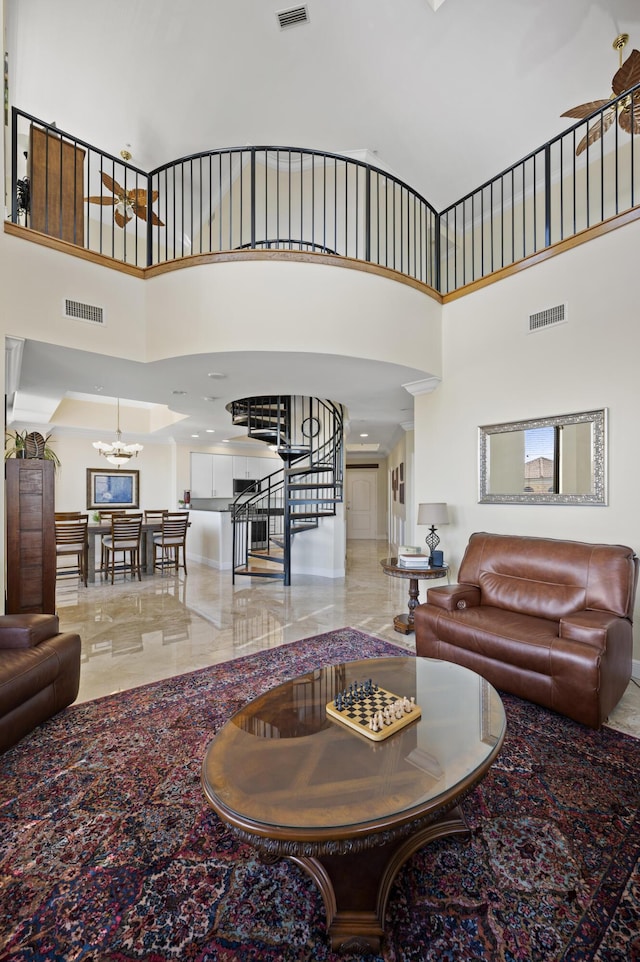 living room with ceiling fan with notable chandelier and a high ceiling