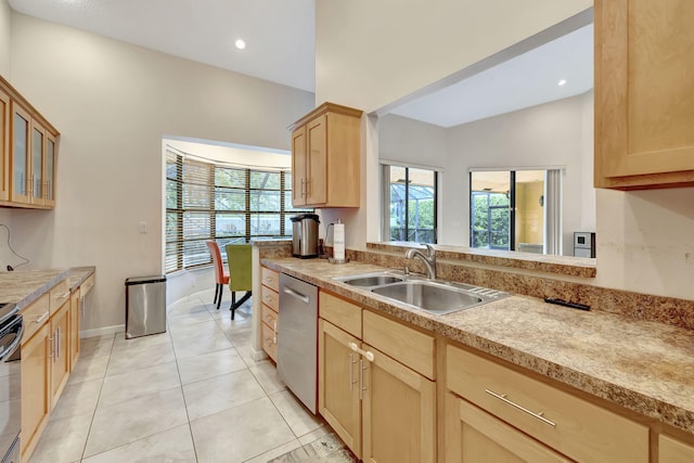 kitchen featuring lofted ceiling, light tile patterned floors, appliances with stainless steel finishes, light brown cabinetry, and sink