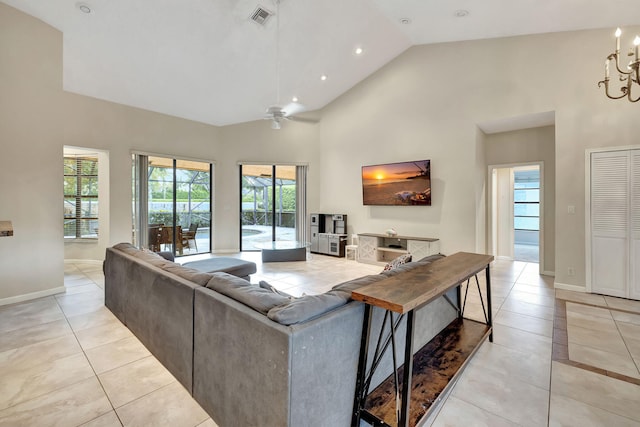 tiled living room featuring high vaulted ceiling and ceiling fan with notable chandelier