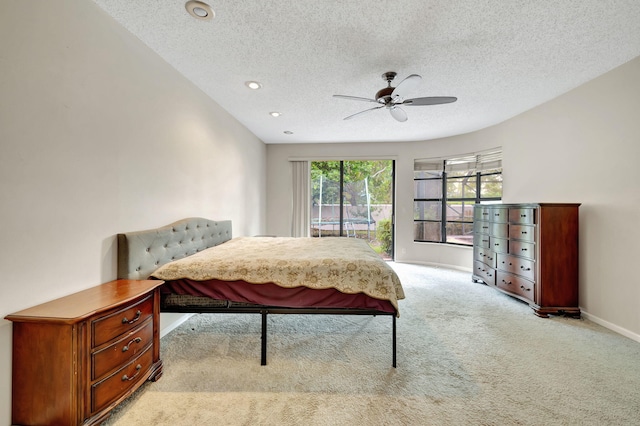 bedroom with ceiling fan, light carpet, and a textured ceiling