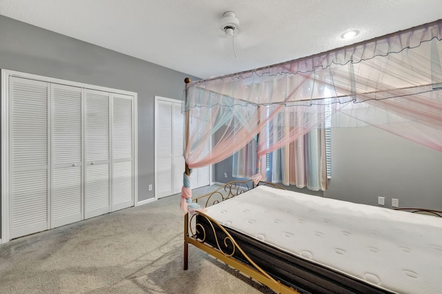 bedroom with ceiling fan, carpet flooring, and two closets