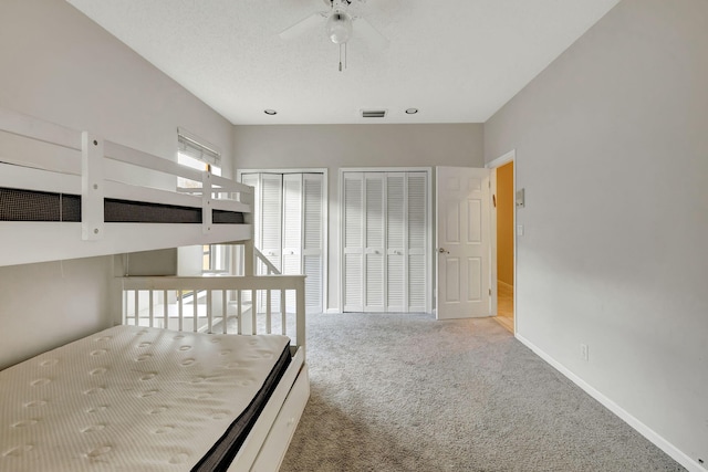 unfurnished bedroom featuring ceiling fan, light carpet, and multiple closets