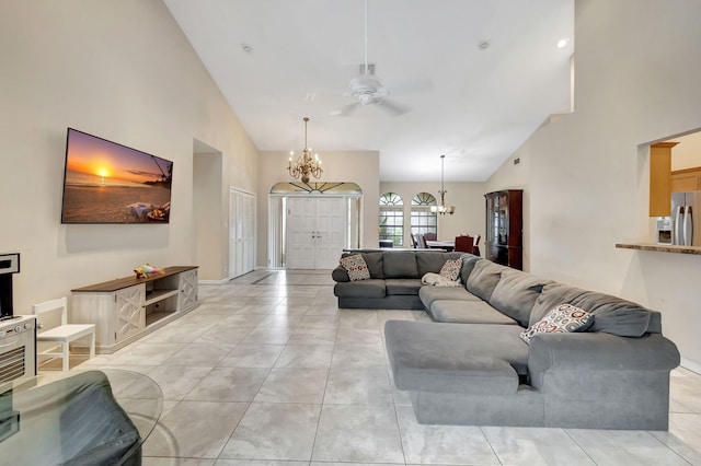 tiled living room featuring high vaulted ceiling and ceiling fan with notable chandelier