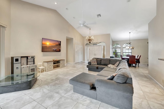 living room with light tile patterned flooring, ceiling fan with notable chandelier, and high vaulted ceiling