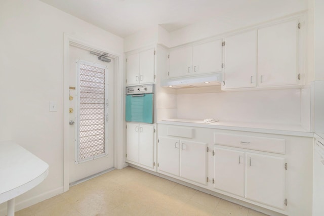 kitchen featuring electric stovetop, oven, and white cabinetry