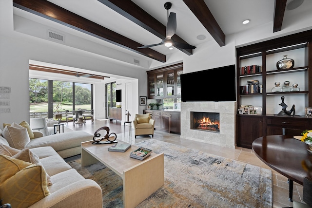 living room featuring a tile fireplace, beamed ceiling, and ceiling fan