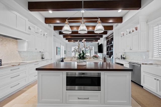 kitchen with beamed ceiling, a center island, white cabinetry, decorative light fixtures, and butcher block countertops