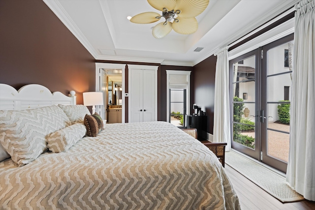 bedroom with wood-type flooring, a tray ceiling, access to outside, and ceiling fan