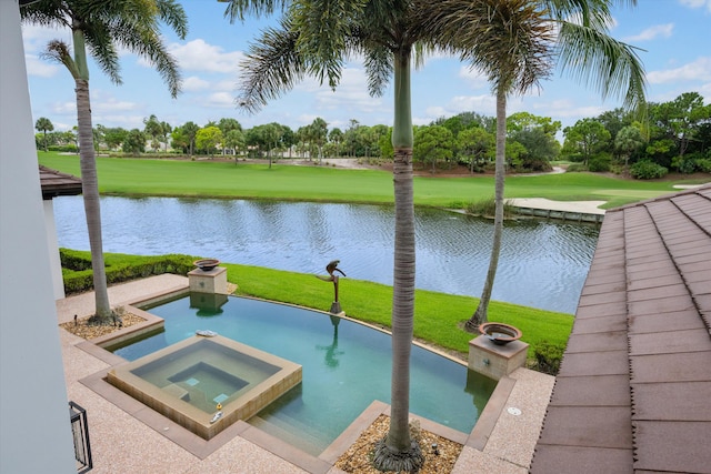 view of swimming pool featuring a lawn, a water view, and an in ground hot tub