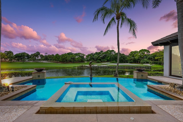 pool at dusk featuring an in ground hot tub and a water view