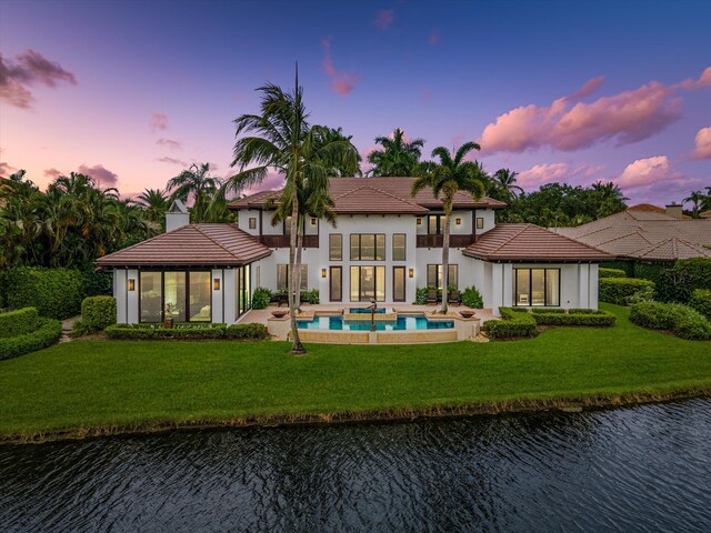 back house at dusk featuring a gazebo, a yard, and a water view