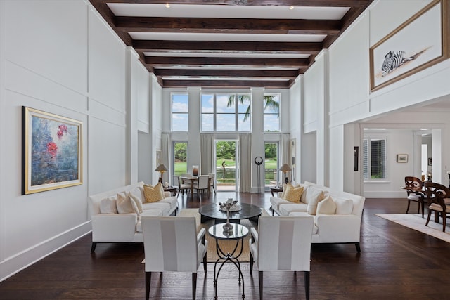 living room with a towering ceiling, beam ceiling, and dark hardwood / wood-style flooring