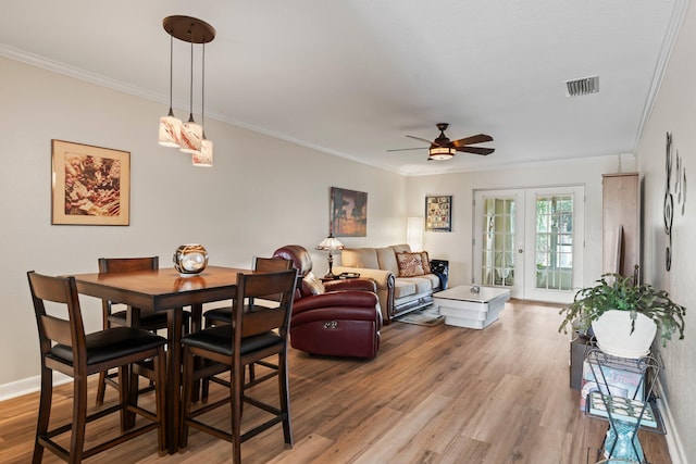 dining area featuring wood-type flooring, crown molding, french doors, and ceiling fan