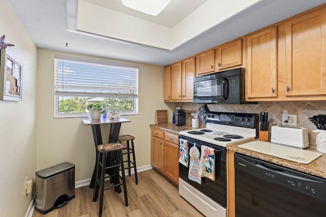 kitchen with light stone countertops, backsplash, black appliances, and light wood-type flooring