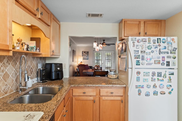 kitchen with light stone counters, ceiling fan, decorative backsplash, sink, and white fridge