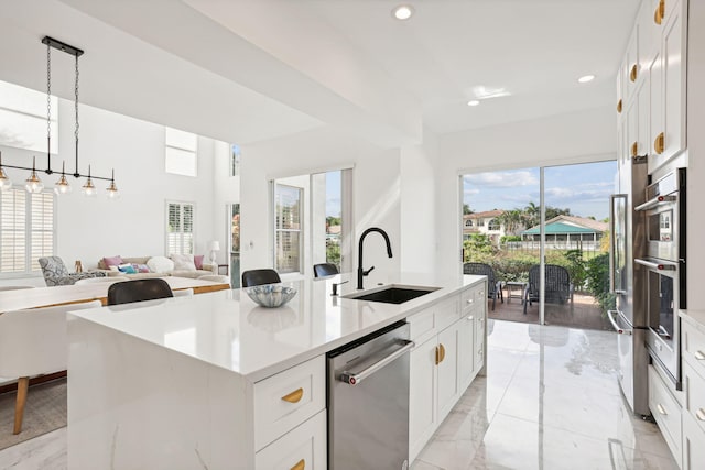 kitchen with sink, stainless steel appliances, an island with sink, and a wealth of natural light