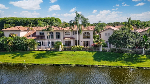 back of house with a balcony, a water view, and a yard