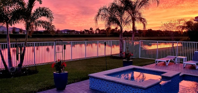 pool at dusk with a patio area, a yard, and an in ground hot tub