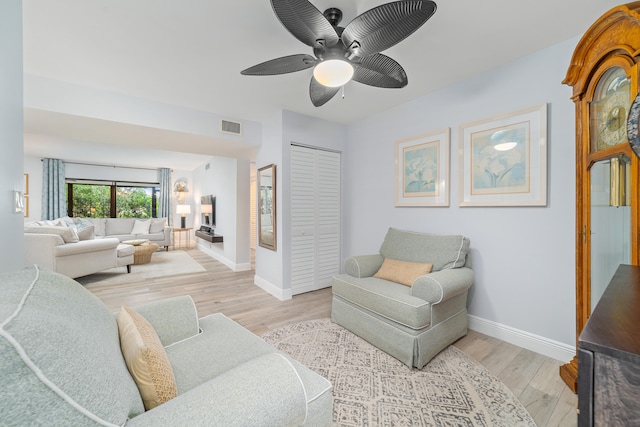 living room featuring light hardwood / wood-style flooring, ceiling fan, and a fireplace