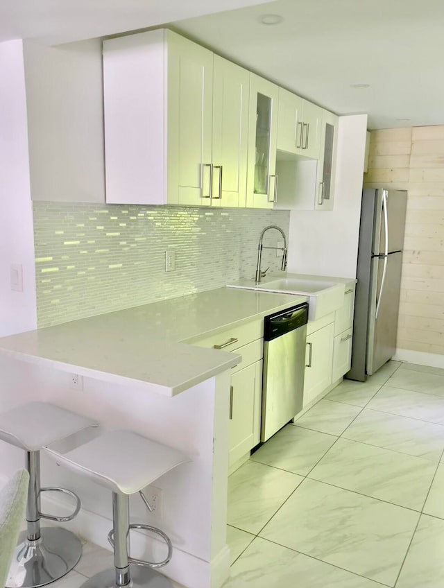 kitchen featuring appliances with stainless steel finishes, a kitchen bar, sink, and white cabinets