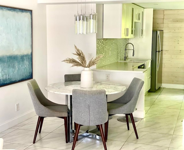 dining space with wooden walls, light tile patterned floors, and sink