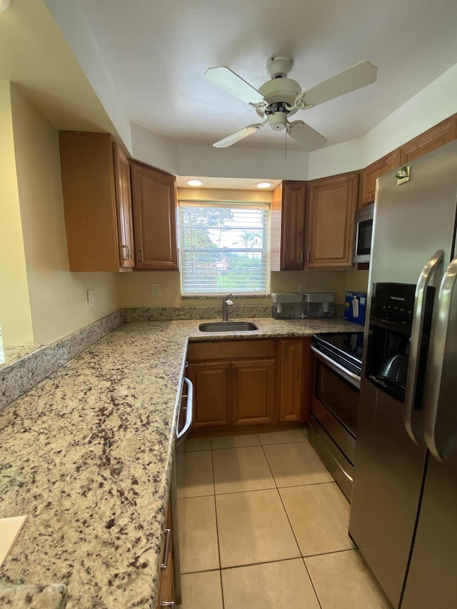 kitchen with light stone countertops, sink, ceiling fan, stainless steel appliances, and light tile patterned floors