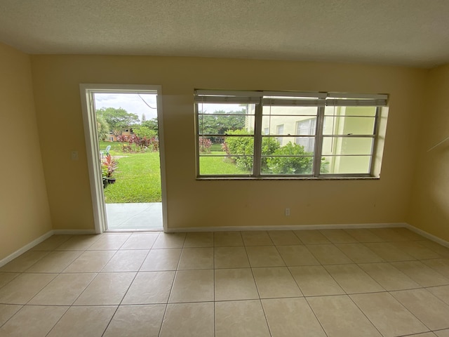 spare room with light tile patterned flooring and a textured ceiling