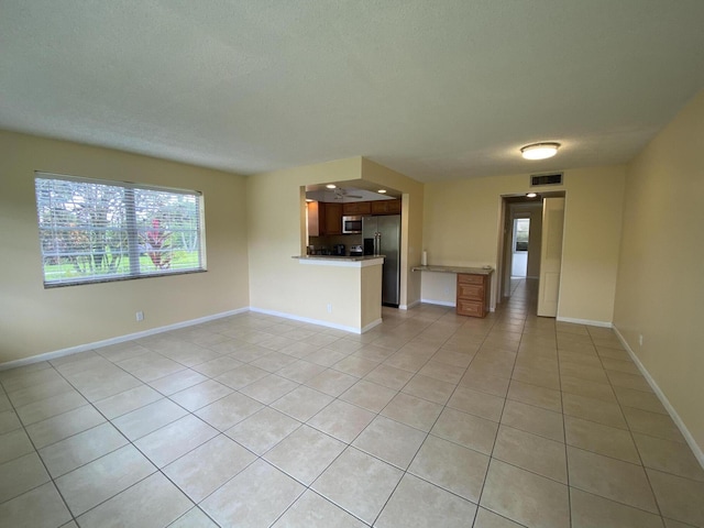 unfurnished living room featuring light tile patterned floors and a textured ceiling