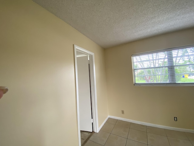 tiled empty room with a textured ceiling