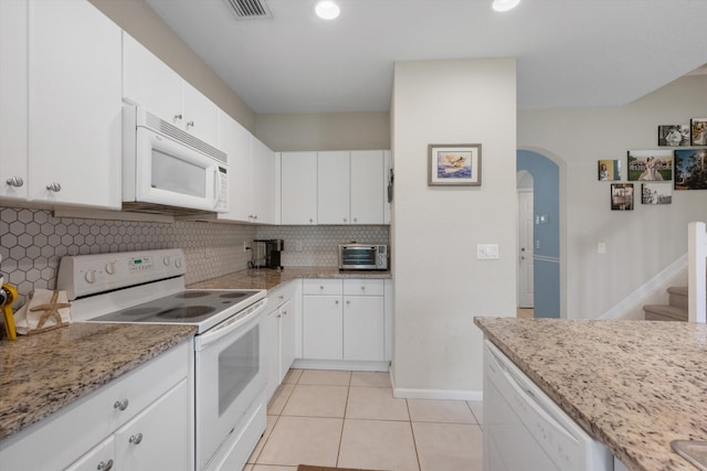 kitchen featuring white appliances, white cabinets, light stone countertops, light tile patterned floors, and tasteful backsplash