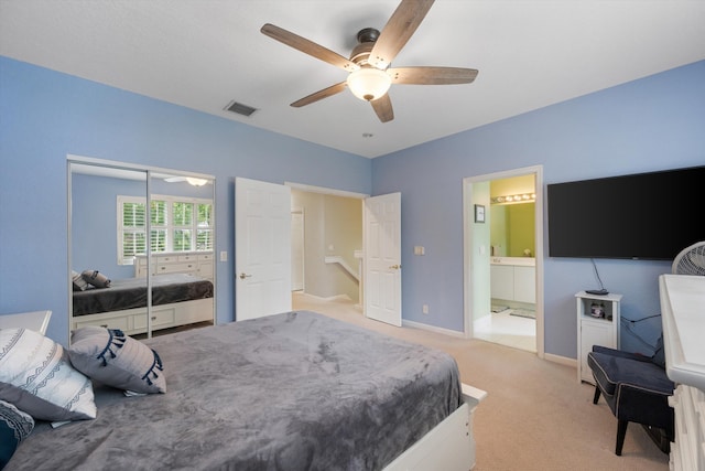 carpeted bedroom with ensuite bath, ceiling fan, and a closet