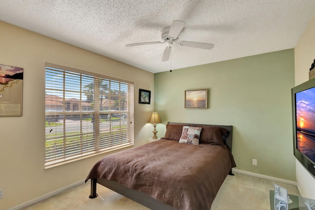 bedroom featuring ceiling fan, a textured ceiling, light carpet, and multiple windows