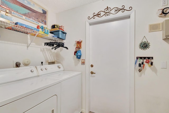 laundry room with washer and clothes dryer and a textured ceiling