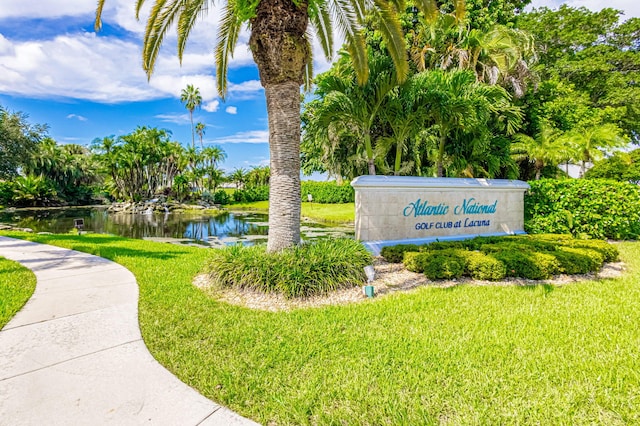 community / neighborhood sign featuring a water view and a yard