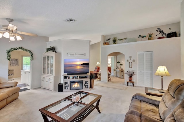 living room with ceiling fan, light colored carpet, and a textured ceiling