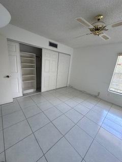 unfurnished bedroom with light tile patterned floors, a closet, and ceiling fan