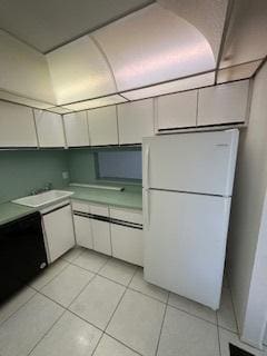 kitchen with white cabinets, white refrigerator, and light tile patterned floors