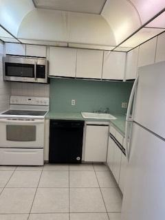 kitchen featuring white appliances, white cabinetry, sink, and light tile patterned flooring