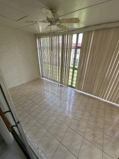 spare room featuring light tile patterned floors, wooden walls, and ceiling fan