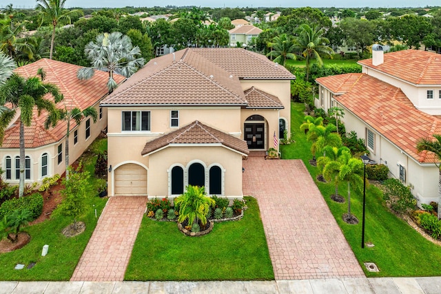 mediterranean / spanish home featuring a front yard and a garage