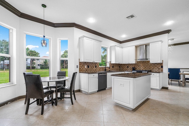 kitchen featuring hanging light fixtures, ornamental molding, wall chimney range hood, white cabinetry, and black dishwasher