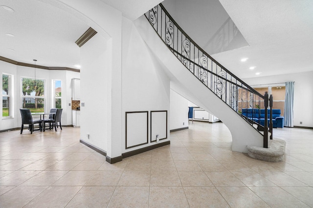 stairway with crown molding, tile patterned floors, and a textured ceiling