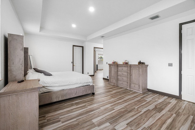 bedroom featuring light hardwood / wood-style flooring and a tray ceiling