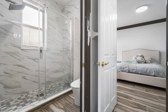 bathroom featuring wood-type flooring, ornamental molding, a shower with door, and toilet